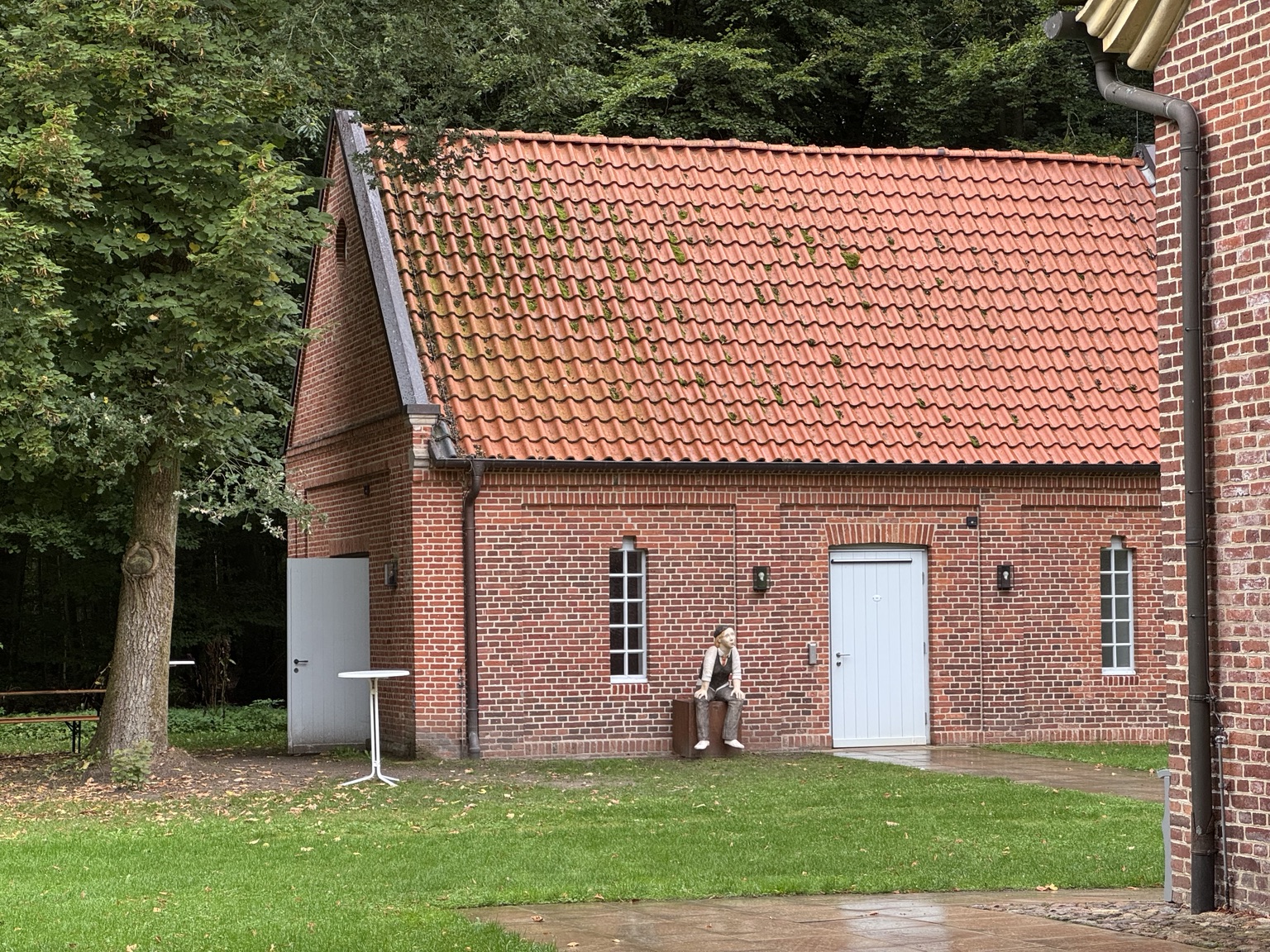 Zittend beeld tegen de muur van een bijgebouw bij Schloss Clemenswerth